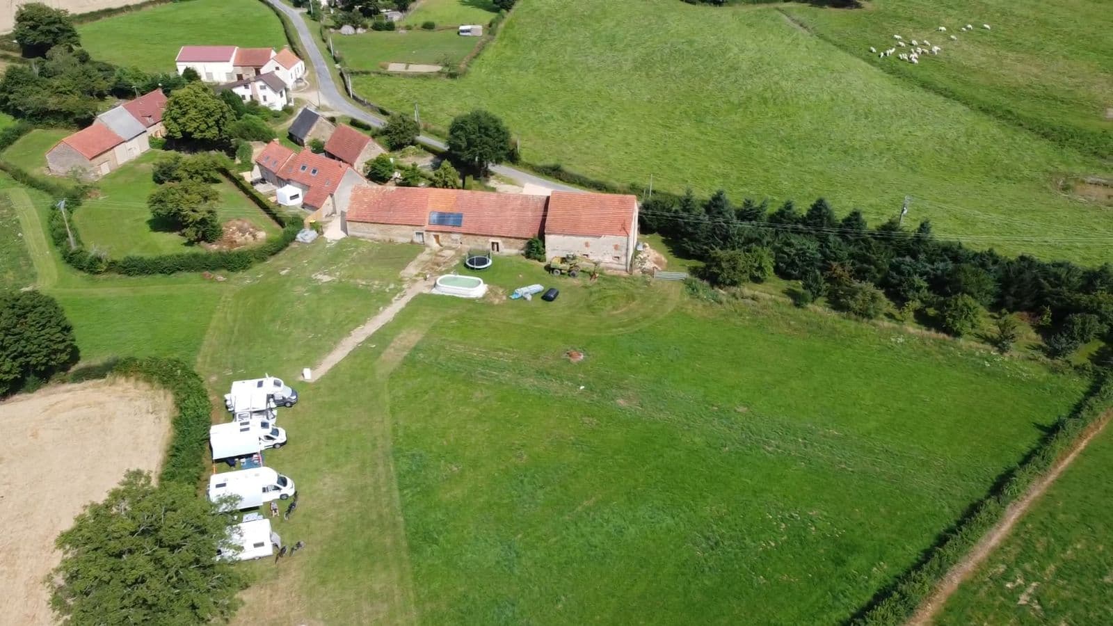 Vue aérienne du Domaine de Villateux : le corps de ferme et les campeurs dans le pré