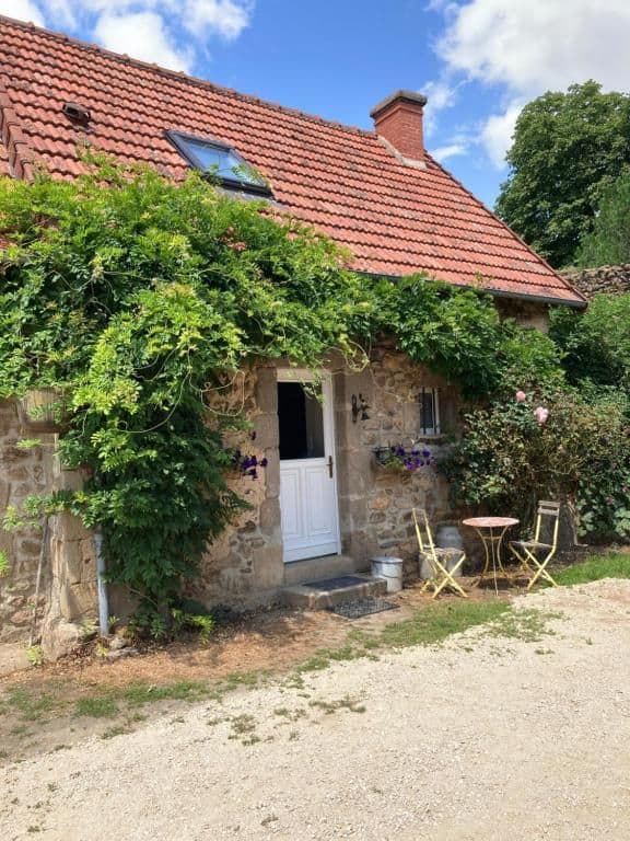 La façade en pierre du gîte, glycine en fleurs et porte blanche